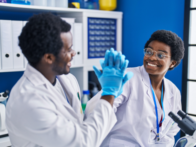 two scientists high-fiving in blue gloves