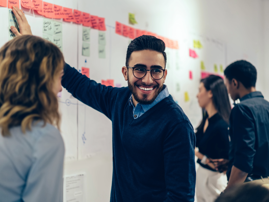 man putting up post-it-notes on a board